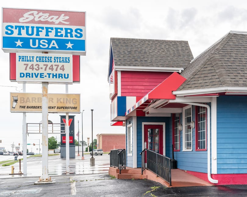 Steak Stuffers USA restaurant with a large sign advertising Philly Cheese Steaks and drive-thru.